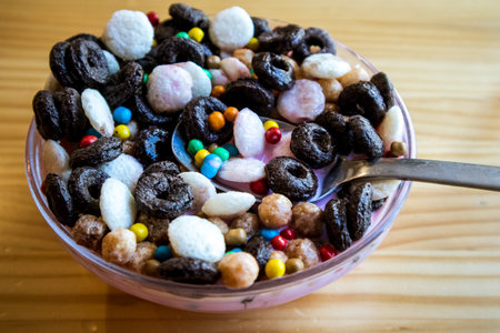Dry breakfast in round plate bowl. Macro food photo of delicious cornflakes, corn rings. Useful healthy morning brunch for kids, children. Different type cereals, multicolored bright balls flatly.の写真素材
