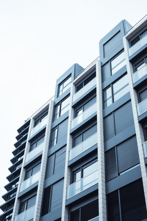 A gray blue facade of a modern multistory residential building, house view from a bottom up. Home...