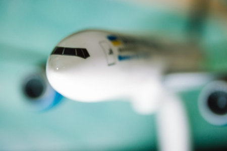 The nose of a white toy airplane, airliner on a blue green background. Aircraft, transportation for...