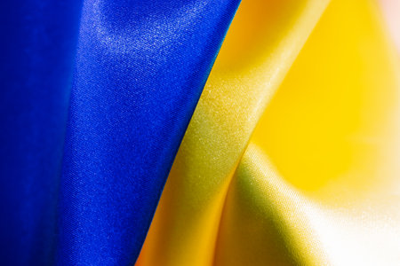 Fabric curved flag of Ukraine. Blue yellow Ukrainian flag abstract background wallpaper. Waving national silk flag texture. Fabric satin textile fragment. National county independence symbol.の写真素材
