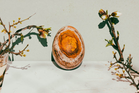 Easter egg with natural brown stone texture on green background Spring still life with blooming tree branches white flowers. Cinematic vintage authentic Easter holiday concept photo Springtime holidayの写真素材