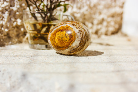 Easter egg with natural brown golden yellow stone texture on beige background. Spring still life with springtime holiday decor. Cinematic vintage authentic Easter concept. minimalist wallpaper.の写真素材
