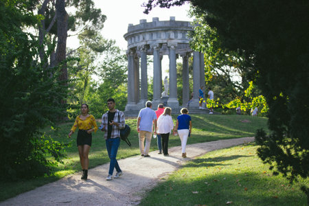 Madrid, Spain. September 1, 2022 Picturesque Capricho Park with an ancient antique stone gazebo on top. Spanish sculptures and landmarks. Botanical garden pavilion. People walking in a city parkのeditorial素材