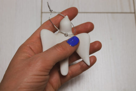 White cute decorative bird swallow in a woman's hand with blue manicure. Suspension made of concrete or porcelain for Christmas tree. A toy sparrow decorative figure for Easter spring holidays.の写真素材