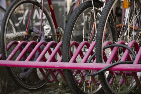 Bicycle rack. Pink bike rack in an urban environment. Reliable place to park Citybike on lock. Eco-friendly transportation. Details of bicycle tires and wheels. Bicycle locked to a metal platform.の写真素材