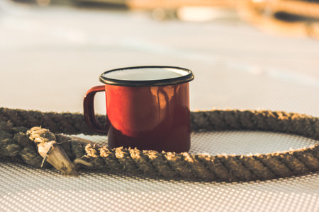 Red cup on a white yacht, ship, boat deck. Concept of tea coffee drinking while traveling at sea ocean, voyage. A mug in the morning sunlight. Nautical wallpaper. Travel around the world concept.の写真素材