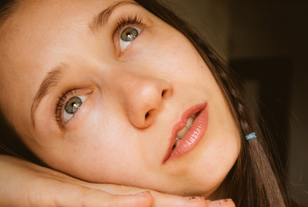 Beautiful white European young woman portrait close-up. A thoughtful, enigmatic girl with gray-blue eyes looking up. Beautiful natural makeup, sensual lips. thoughtful female beauty. dream mood.の写真素材