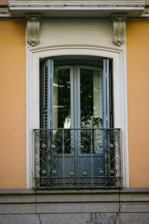 Vertical vintage balcony with blue wooden door in classic architectural style. Orange facade of residential building with decorative elements, stucco in retro old style. Spanish architecture exteriorの写真素材
