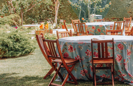 Beautifully set tables with floral tablecloths. Private backyard party. Comunion in Spain, traditional catholic holiday celebration, fiesta in nature. Garden furniture, round wooden tables and chairs.の写真素材