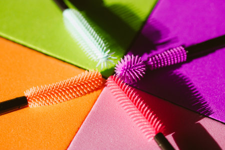 Set of multicolored silicone mascara brushes on a multicolored bright background. Green, pink, purple, orange lash brushes. Modern decorative cosmetics for women. Female beauty and glamor fashion.の写真素材