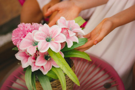 A beautiful bouquet of pink flowers, lilies in the bride's bouquet in a woman's hands. A girl touching a bunch of pinky tropical flowers in bloom in spring garden. Elegant wedding flora. Romantic ceremonyの写真素材
