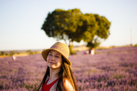 A beautiful dreamy romantic brunette young woman wearing straw hat in blooming lilac lavender field. Female portrait in nature on a summer day. Traveling in Europe. Boho style clothing. Provence Franceの写真素材