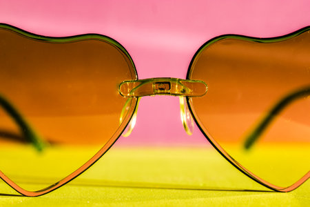Sunglasses with pink glasses in the shape of hearts on a pink green pastel background. Fashion accessories for summer vacation. Female beauty accessory. Summertime fun, travel concept. Valentine's Dayの写真素材