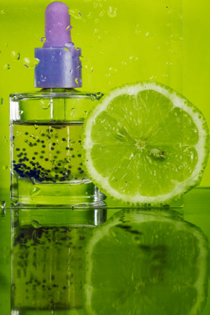 Hyaluronic acid in a glass bottle with a pipette on green background against wet glass and lime slice. Facial Serum or cuticle citrus oil. Hydro boost serum provides active moisturizing for aging skinの写真素材