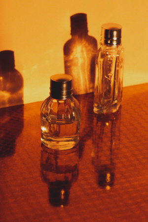 Glass miniature bottles with perfume, essential oil. Presentation of cosmetic products. Facial and body skin care, beauty shop. Women's grooming products on orange yellow vertical background.の写真素材