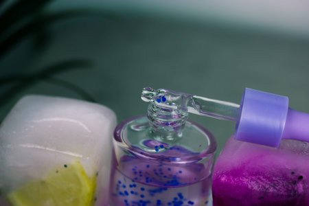Cosmetic serum in a glass bottle with pipette on ice cubes with fresh pitaya or dragon fruit, lemon...