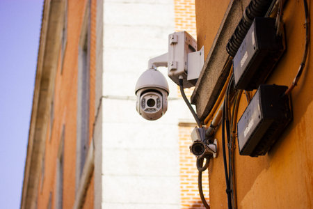 White IP CCTV surveillance camera against yellow tree foliage. Concept of security, private...