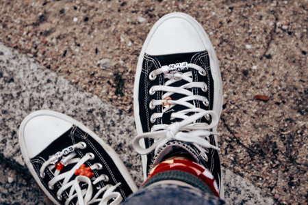 Pair of black and white classic sneakers on women's feet. Crossed legs and comfortable walking...
