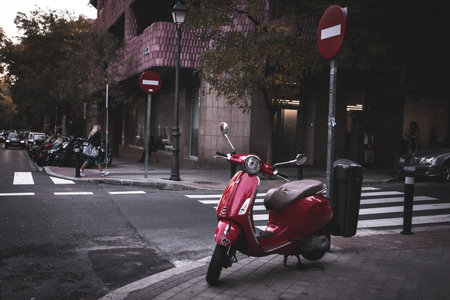 Madrid, Spain. November 19, 2023 Red Piaggio Vespa scooter parked on city street. Eco-friendly...