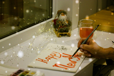 Artist draws inscription Happy New Year with red paint, brush on white sheet of paper. Festive...