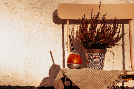 Mate calabash with bombilla. Healthy infused drink, classic Yerba mate tea on a chair on a cozy patio, backyard. Hot beverage on a terrace. Traditional Latin American cuisine. Useful drink still life.の写真素材