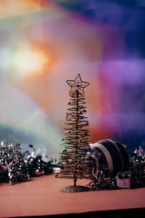 Artificial Christmas tree with a star on a top on colorful background. Decor for celebration New Year 2024, winter vacations, holidays. New Year's Eve festive scene. Vertical banner Gifts and presentsの写真素材