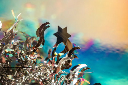 Shiny holographic silvery tinsel, star-shaped tinsel on bright colorful blue background. New Year and Christmas winter holidays 2024 decor. Abstract festive wallpaper. Make a with on a falling starの写真素材
