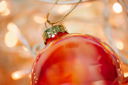 Orange glass ball, Christmas toy among tangled white wires of garland with yellow bulbs lights. New...