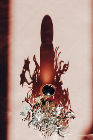 Perfume shadow. Glass cosmetic serum bottle on pink surface, cast shadow. Perfume bottle among...