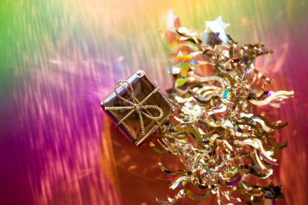 A silver gift box on pink green background. Wrapped present and tinsel. Winter holiday, New Year,...
