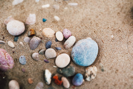 Natural colorful sea round stones on a sandy beach, seashore. Abstract summer holidays background....