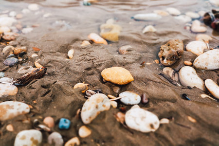 Natural colorful sea stones, rocks on a sandy beach, seashore. Abstract summer holidays background....