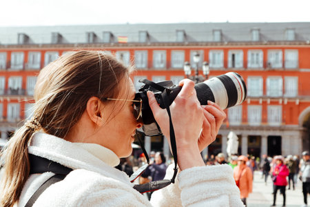 Madrid, Spain. 27 February 2024 A tourist woman making photo of a Plaza Mayor visiting Spanish capital. Traveller photographer Old red building facadeのeditorial素材