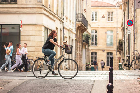 Bordeaux, France. October 8, 2023 European woman riding a bicycle with a small Yorkshire Terrier dog...