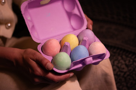 Collection of beautifully painted Easter eggs nestled in a violet box in woman's hands. Vibrant...