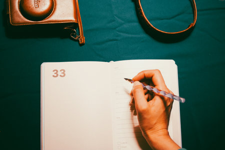 Madrid, Spain. 5 May 2023 Travel blogger woman writing, making notes in open notebook. Vintage photo camera Leica. Journaling, adventure planning.のeditorial素材