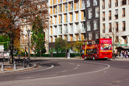 Berlin, Germany. October 1, 2023 Asphalted city street goes into a turn, cars and a red tourist bus for sightseeing trips. Modern buildings facades.のeditorial素材