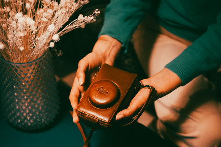 Madrid, Spain. 1 May 2023 Old vintage Leica photo camera in female hands top view on deep blue. Female blogger. A traveller and nature photographer.のeditorial素材