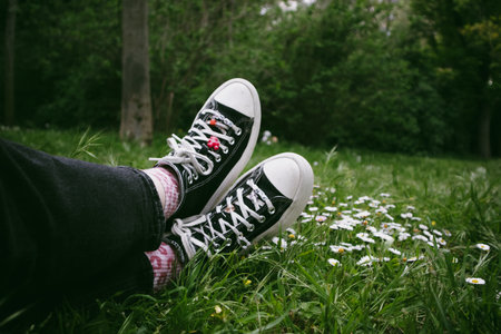 Madrid, Spain. 7 January 2024. Classic Converse sneakers on womens feet. Vintage shoes and green...
