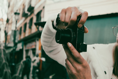 Madrid, Spain. 1 March 2024. A young woman in a white coat takes a photo with a small digital camera...