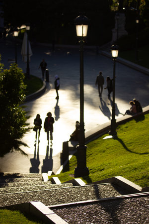 A tall stone staircase leading downward. People walking down the street on a sunny day, contrasting...