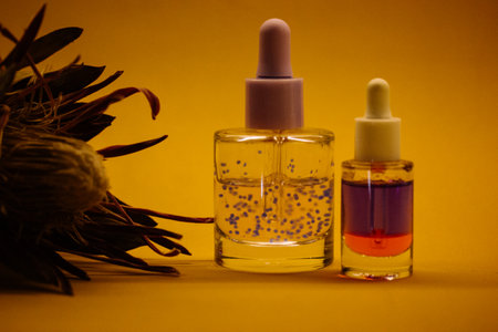 Cosmetic transparent glass dropper pipette bottle on yellow background. Violet serum for moisturizing face body skin care product. Natural cosmetics.の写真素材