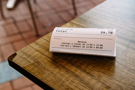 Madrid, Spain. April 1, 2024 Total check receipt for 39,70 euros lies on wooden table in a bar, restaurant. Payment for lunch dinner in a Spanish cafeのeditorial素材