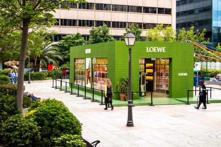 Madrid, Spain. May 1, 2024 Green city street in a spring sunny day. Loewe fashion brand modern shop....