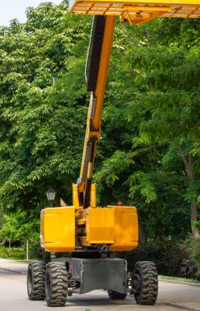High yellow lift crane with platform for garden works, trees care. Cutting tree on a high. Hydraulic...