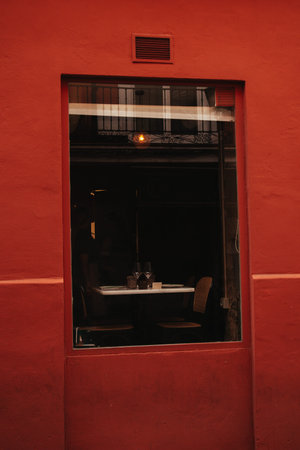 Red facade of building with large window of cafe, restaurant with table. Details of bright European...