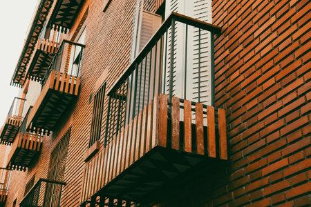 Open balcony and facade of brown brick residential house. Urban buildings and facades. Detail of a...