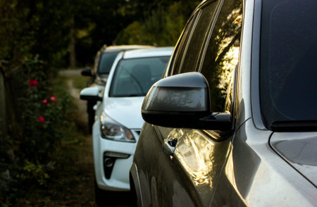 Side view of cars parked one after another on a country road, village street in twilight. Gray car...