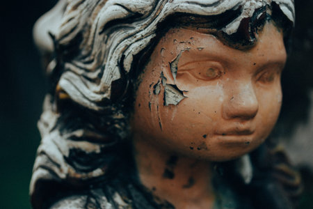 Worn stone angel. Vintage female figurine with shabby paint on her face. Monument in a cemetery. Old...