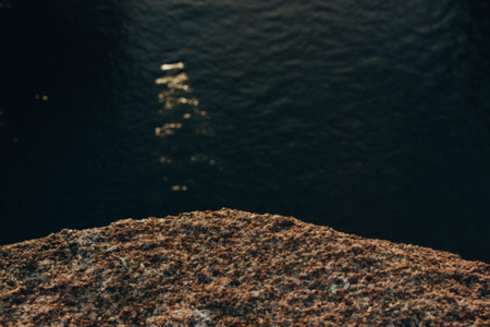 Rock podium. Seashore and stone parapet texture. Dark water in a sea, ocean aerial view selective focus. Dark key abstract seascape background.の写真素材